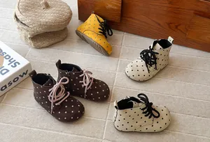 Close-up of stylish polka dot baby boots in multiple colors on a textured floor