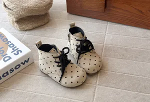 Macro view of toddler girl's polka dot suede boots with black laces and side zipper