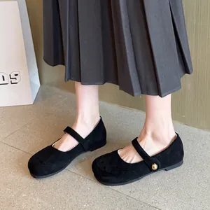 Détail élégant de ballerines Mary Jane en daim noir avec bouton doré et bride fine