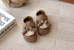 Vista detallada de zapatos de ante marrón para niñas con parche de dibujos animados