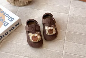 Detalle de zapatos de ante marrón para niña con un lindo parche de oso a cuadros
