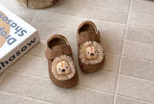 Detalle de zapatos de ante marrón para bebé con un lindo diseño de león en 3D con flecos