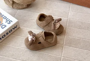 Primer plano de zapatos de gamuza marrón para bebé con lindo personaje de dibujos animados.