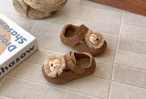 Vista detallada de mocasines de gamuza marrón para niñas con un diseño de león tierno.