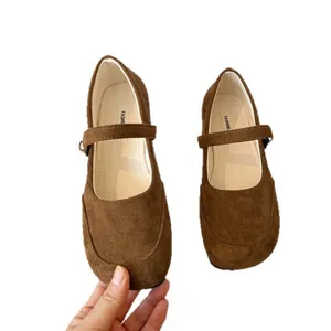 Gros plan de chaussures plates Mary Jane en daim marron à texture veloutée.