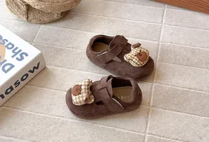 Detalle de zapatos de gamuza marrón para niños con oso de dibujos animados y velcro