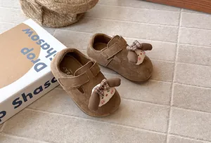 Primer plano de zapatos de ante marrón para niña con lindo conejo de dibujos