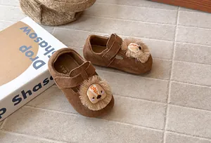 Vista detallada de mocasines de gamuza marrón para niña con cara de león de dibujos.