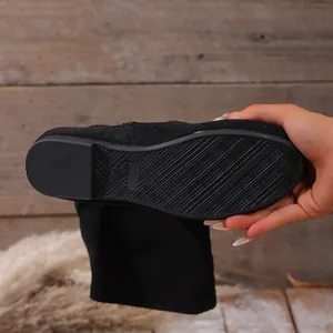 Detailed macro view of the anti-slip rubber sole on flat black suede mid-calf boots