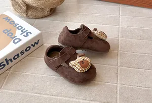 Primer plano de zapatos de ante marrón para niñas con cabeza de oso de dibujos