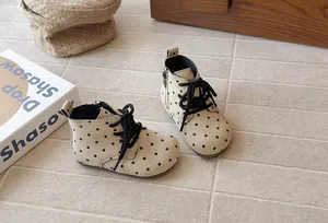 Close-up detail of beige polka dot girl's boots with side zipper and black laces