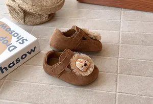 Primer plano detallado de zapatos de gamuza marrón para niños con diseño de león animado