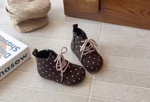 Close-up detail of brown polka dot girls' ankle boots with pink laces