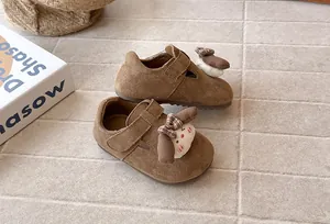 Detalle de zapatos de ante marrón para niña con un lindo perro y lazo de cuadros