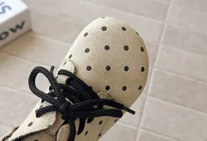Macro detail of the stylish black polka dot pattern on beige suede girls' boots