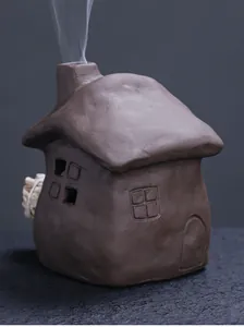 Close-up of ceramic house incense burner with smoke rising from the chimney