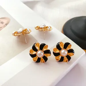 Détail de boucles d'oreilles fleurs en émail baroque vintage avec perles centrales