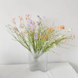 Detailansicht bunter künstlicher Wildblumen in einer gerippten Glasvase auf Tisch
