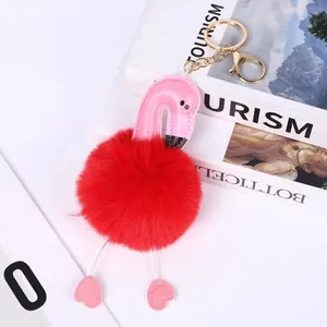 Close-up of a pink flamingo pompom keychain with a red faux fur ball and gold clasp