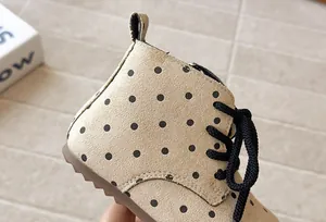 Detailed view of beige polka dot girls Martin boots featuring black laces and soft soles.