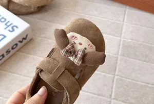 Primer plano de mocasines de gamuza marrón para niña con lindo personaje de dibujos.