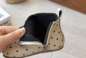 Close-up detail of girls' polka dot ankle boots showing side zipper and lining