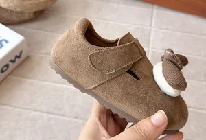Detalle de zapato de gamuza marrón para niña con decoración de ardilla animada