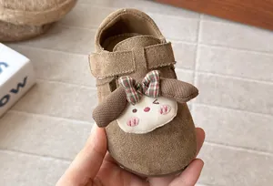 Primer plano de zapato de ante marrón para niños con adorno de perrito y lazo de cuadros.