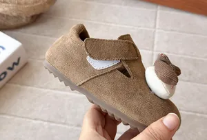 Primer plano de zapatos de gamuza marrón para niños con decoración de conejo de peluche