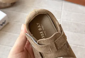 Detalle de zapato de gamuza marrón para niña con suela blanda y cierre de velcro