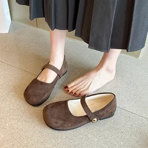Gros plan de chaussures Mary Jane en daim marron avec bride et bouton doré