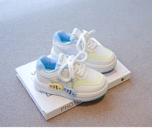 Vista detallada de zapatillas blancas para niña con toques azul claro sobre libros.