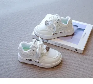 Detalle de zapatillas blancas para niñas con motivos de gato y pez sobre un libro