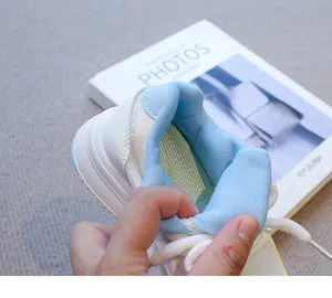 Primer plano del forro de malla azul y el talón acolchado de las zapatillas blancas niña