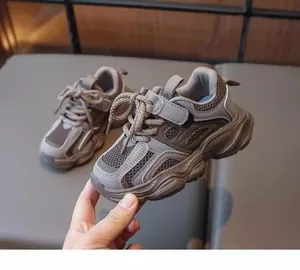 Detailed view of breathable mesh girl's dad sneakers in earth tones held by hand