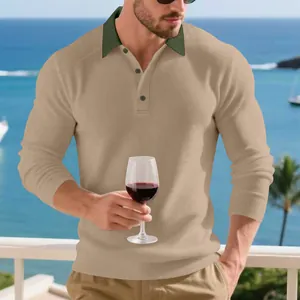 Homme élégant portant un polo en maille côtelée kaki avec col vert contrasté au bord de la mer.