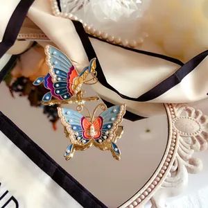 Close-up of vintage enamel butterfly brooch with pearl details reflected on mirror