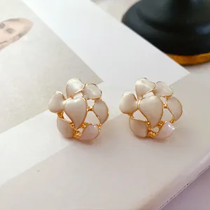 Nahaufnahme von Vintage-Emaille-Blumenohrsteckern mit cremefarbenen Blütenblättern