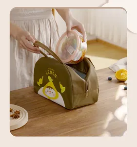 Detail view showing a glass lunch box being placed into a lemon cartoon insulated bag