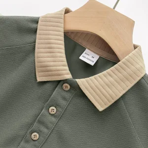 Détail d'un polo vert à manches longues en maille côtelée lourde sur un cintre.