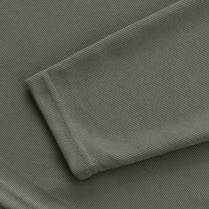 Gros plan détaillé du tissu en maille côtelée vert olive et des coutures du poignet de polo