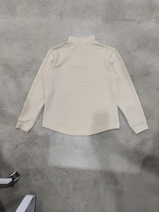 Dettaglio del retro di una felpa beige da uomo con mezza zip e trama a nido d'ape.