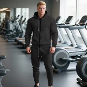 Hombre con sudadera con capucha negra y pantalones de chándal a juego en un gimnasio