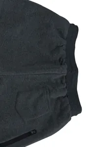 Detalle de pantalón de chándal gris oscuro con cintura elástica y bolsillo con cremallera.