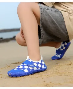 Close-up detail of blue and white checkered pattern kids' water shoes on a sunny sandy beach