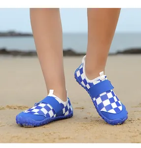 Detailed view of children's blue and white checkered water shoes on a sandy beach