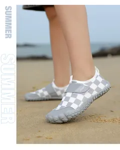 Detailed macro view of children's grey checkered water shoes being worn on a sandy beach