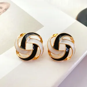 Close-up detail of vintage round hollow enamel stud earrings in black white and gold