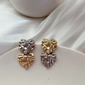 Detailed view of two-tone wrinkled heart stud earrings in gold and silver finish