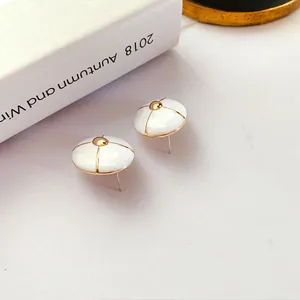 Macro detail of vintage white enamel stud earrings with gold trim and 925 silver needle